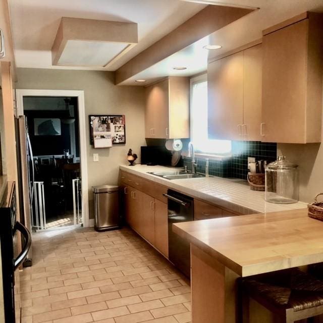 kitchen featuring decorative backsplash, light countertops, a peninsula, and a sink