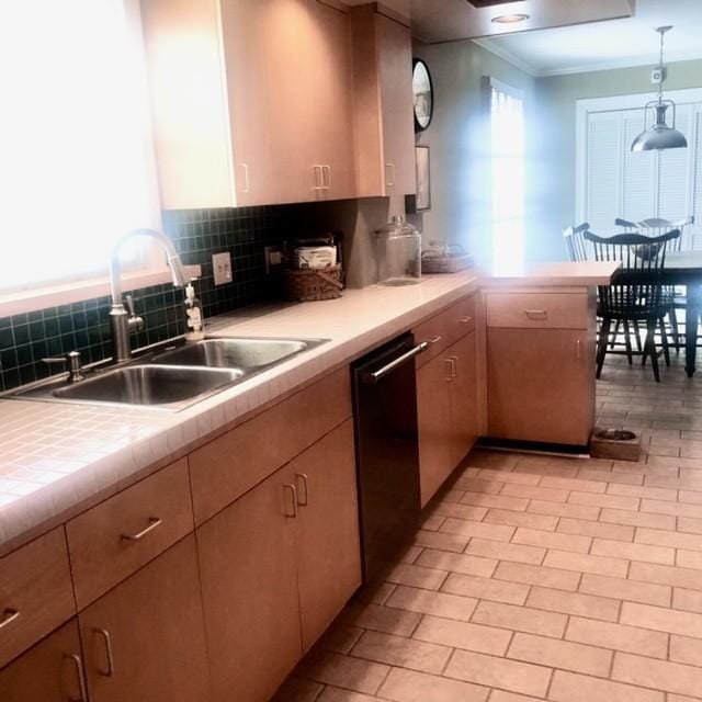 kitchen featuring dishwashing machine, a peninsula, a sink, decorative backsplash, and pendant lighting