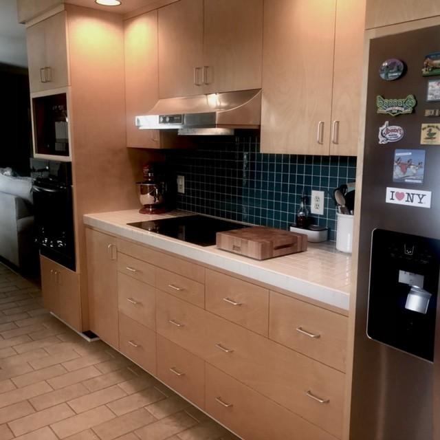 kitchen featuring extractor fan, light countertops, black appliances, and backsplash