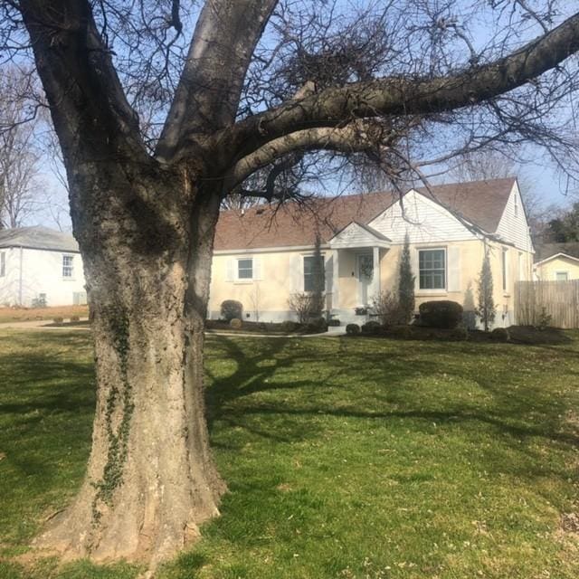 view of front of property with a front yard, fence, and stucco siding