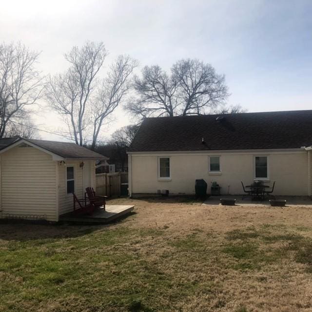 back of property featuring a yard, an outbuilding, and a wooden deck