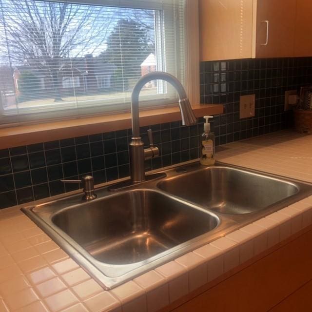 room details with a sink, backsplash, white cabinets, and tile countertops