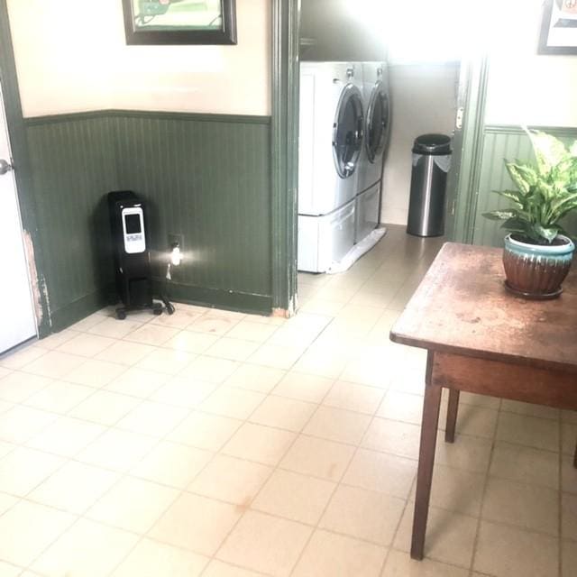 laundry room with wood walls, wainscoting, laundry area, and washer and clothes dryer