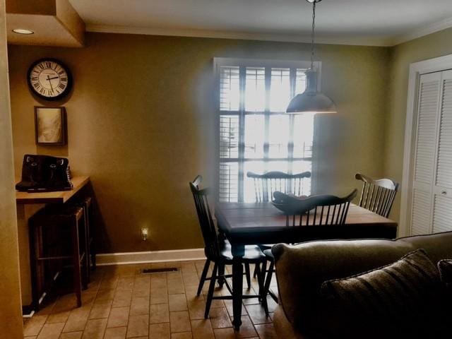 dining room with light wood finished floors, visible vents, crown molding, and baseboards