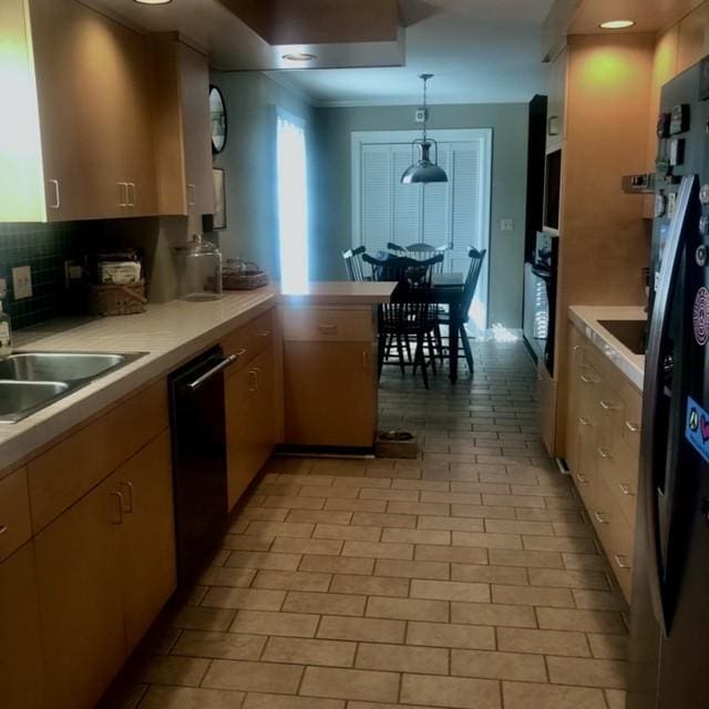 kitchen featuring decorative backsplash, dishwasher, hanging light fixtures, and light countertops