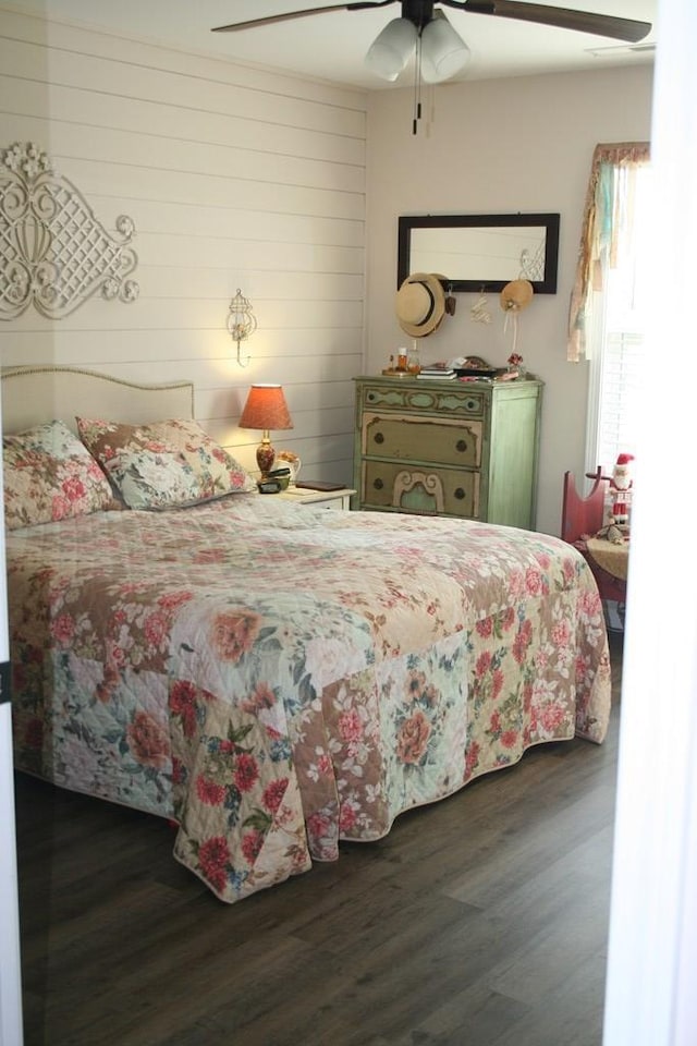 bedroom featuring wood finished floors, wood walls, and ceiling fan