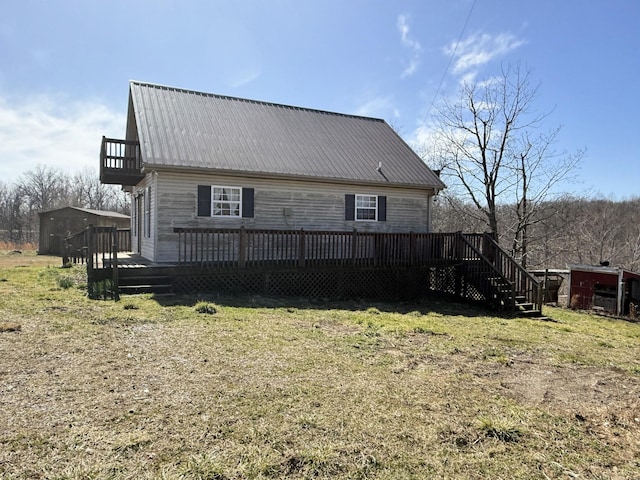 back of property with an outbuilding, a yard, a wooden deck, and metal roof