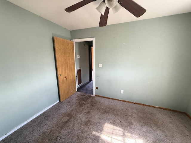 carpeted spare room featuring baseboards and ceiling fan