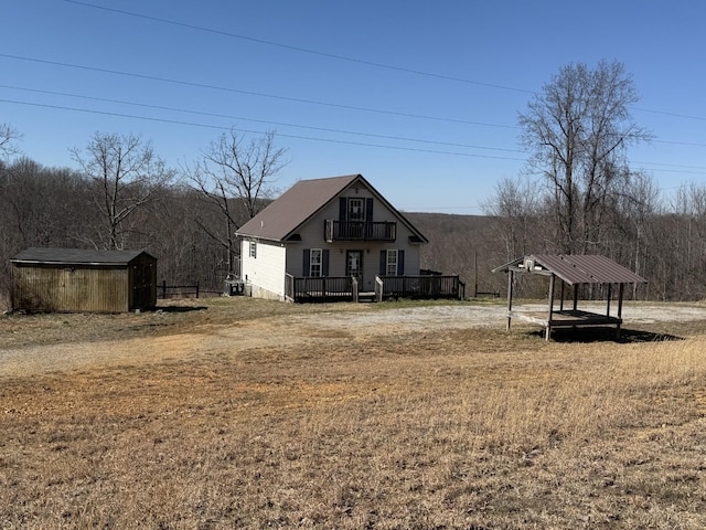 view of yard featuring a deck, an outdoor structure, dirt driveway, and a storage shed