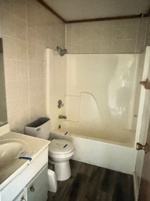 full bath with toilet, shower / tub combination, wood finished floors, tile walls, and vanity