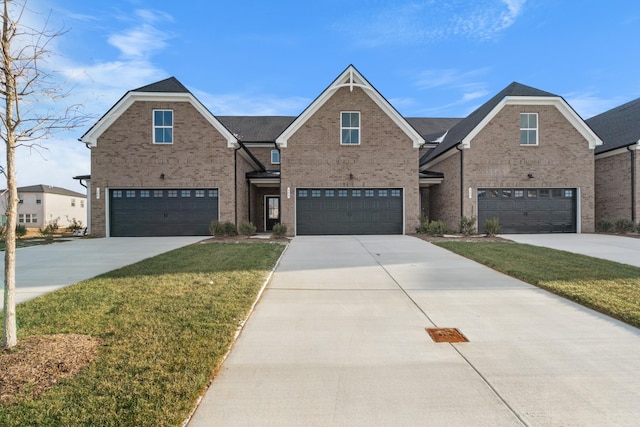 traditional-style home featuring a front lawn, an attached garage, brick siding, and driveway