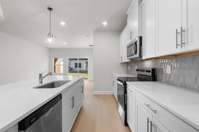 kitchen featuring a sink, white cabinets, appliances with stainless steel finishes, pendant lighting, and backsplash