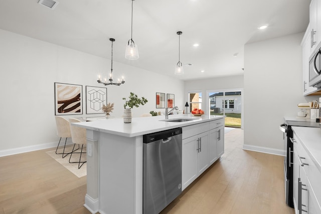 kitchen with a sink, appliances with stainless steel finishes, a center island with sink, and light wood finished floors