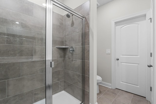 full bath featuring tile patterned floors, toilet, and a stall shower