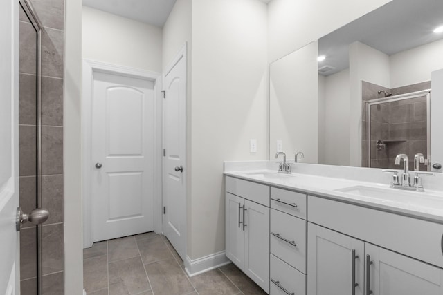 bathroom featuring a sink, a stall shower, double vanity, and tile patterned floors