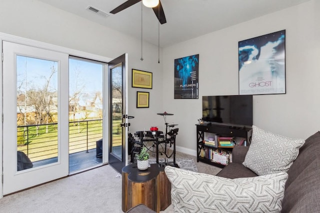 living room featuring carpet flooring, a ceiling fan, visible vents, and baseboards