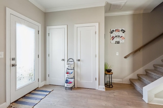 foyer featuring visible vents, stairway, crown molding, light wood finished floors, and baseboards