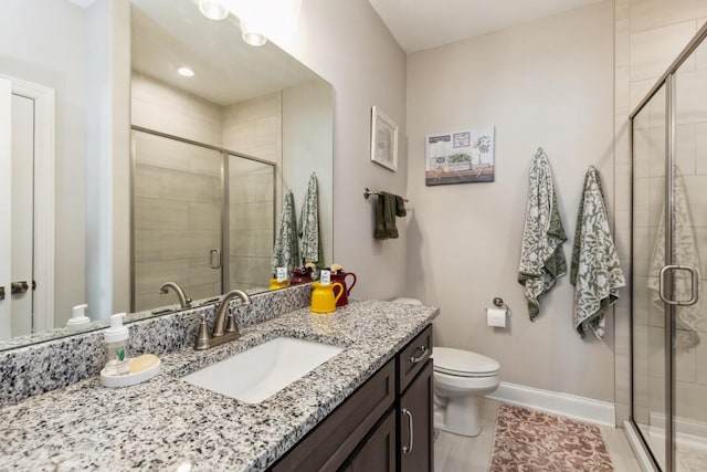 bathroom featuring baseboards, toilet, a stall shower, and vanity