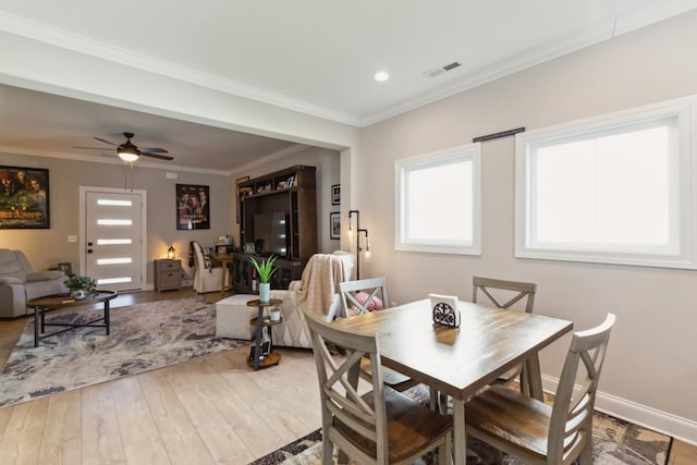 dining room with wood finished floors, baseboards, visible vents, ceiling fan, and ornamental molding