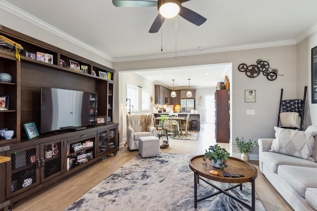 living area with crown molding, light wood-style flooring, and ceiling fan