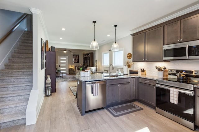 kitchen featuring dark brown cabinets, open floor plan, appliances with stainless steel finishes, a peninsula, and a sink