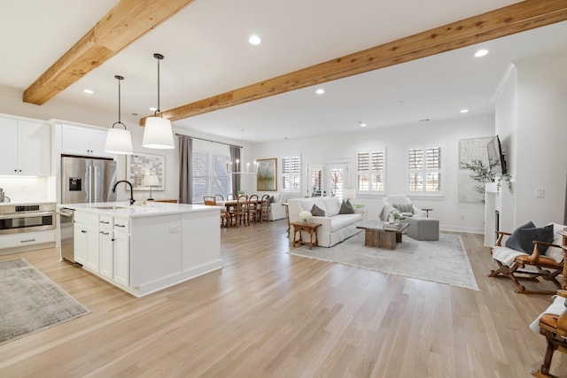 kitchen with beam ceiling, open floor plan, a wealth of natural light, and a sink