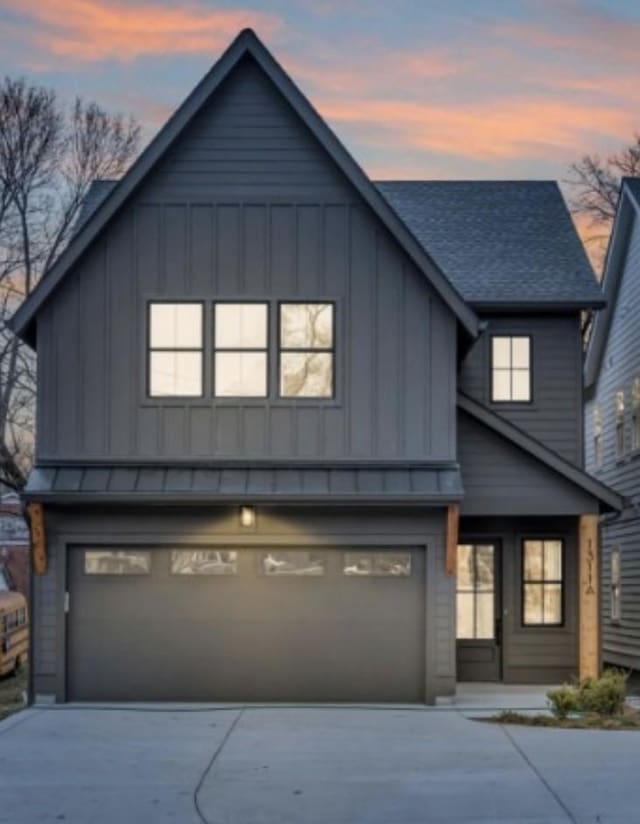 view of front of home featuring board and batten siding, concrete driveway, a garage, and roof with shingles