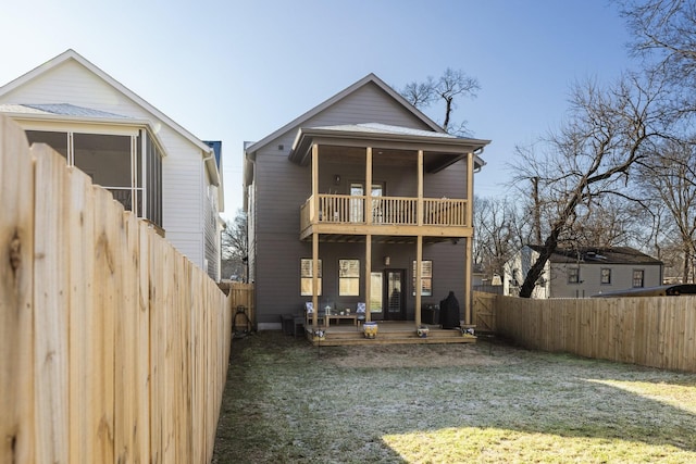 back of property featuring a balcony, a yard, and a fenced backyard