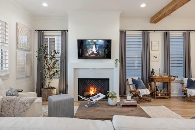 living room with recessed lighting, a warm lit fireplace, crown molding, and wood finished floors