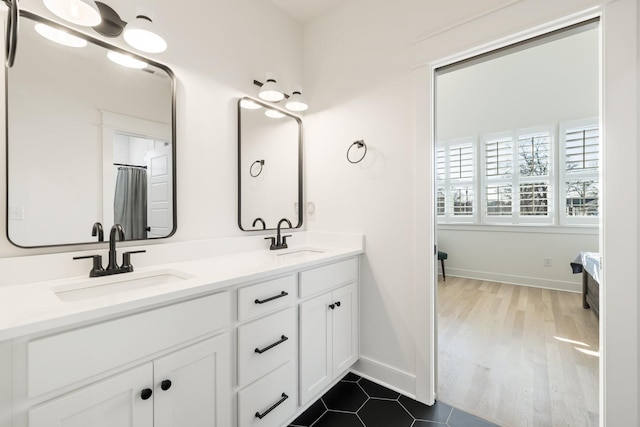 full bathroom with double vanity, baseboards, and a sink