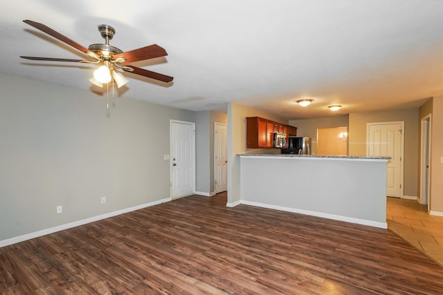 unfurnished living room with ceiling fan, baseboards, and wood finished floors