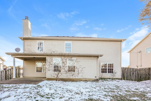 snow covered house with fence and a chimney