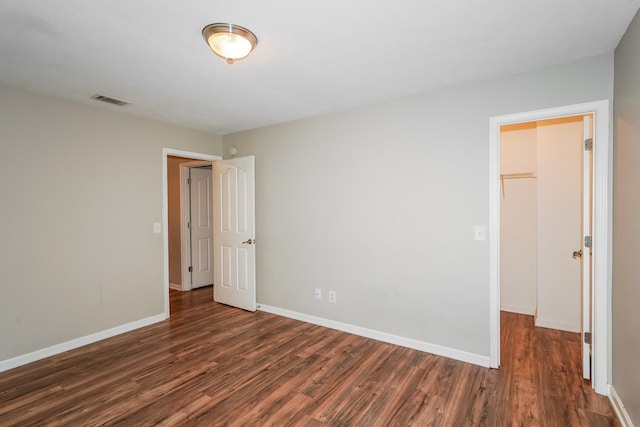 spare room featuring visible vents, baseboards, and dark wood-style flooring