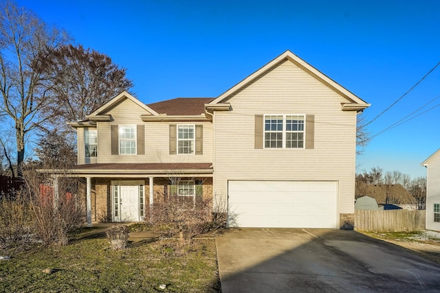 traditional home featuring a garage, brick siding, driveway, and fence