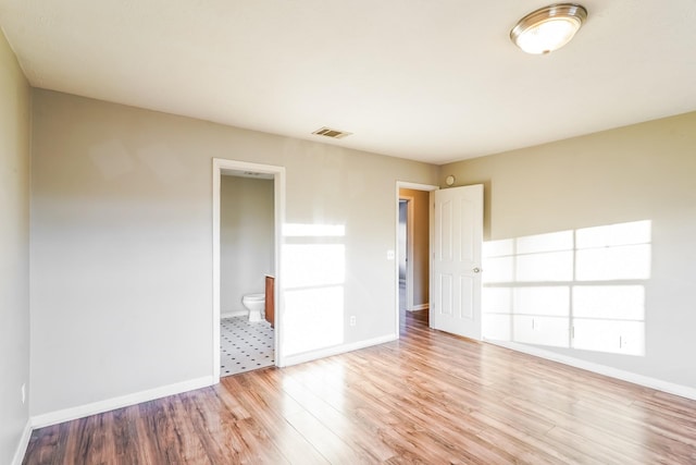 spare room featuring visible vents, baseboards, and wood finished floors