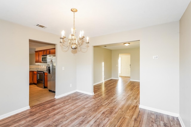 unfurnished room featuring visible vents, baseboards, and light wood-style floors