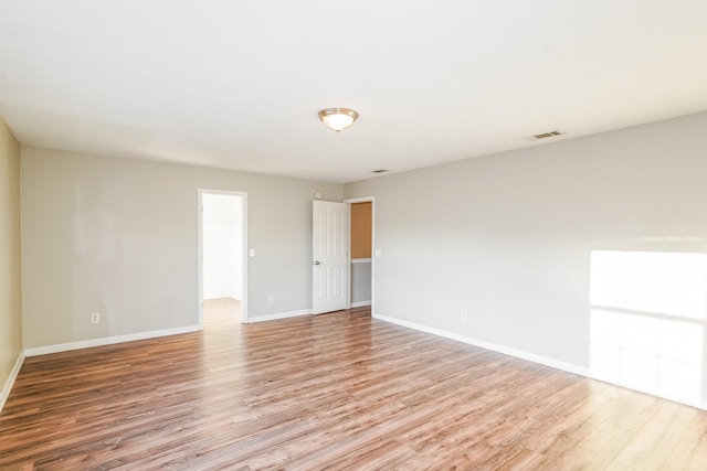 spare room with light wood-style floors, visible vents, and baseboards