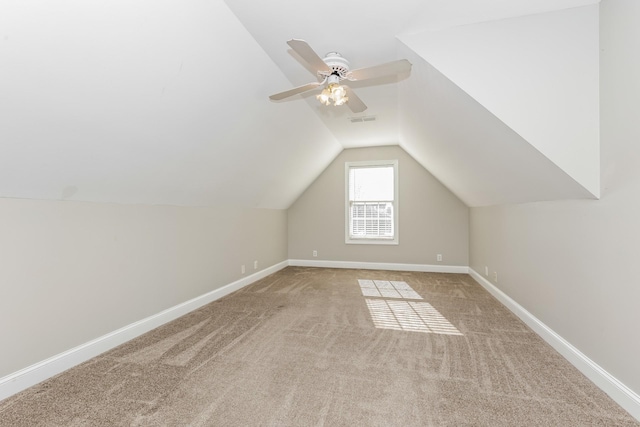 additional living space featuring visible vents, carpet, baseboards, lofted ceiling, and a ceiling fan