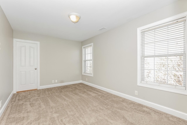 empty room with visible vents, baseboards, and light carpet