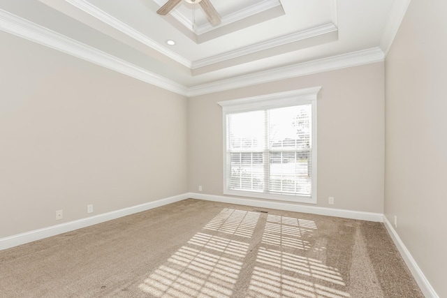 carpeted empty room with a tray ceiling, a ceiling fan, crown molding, and baseboards