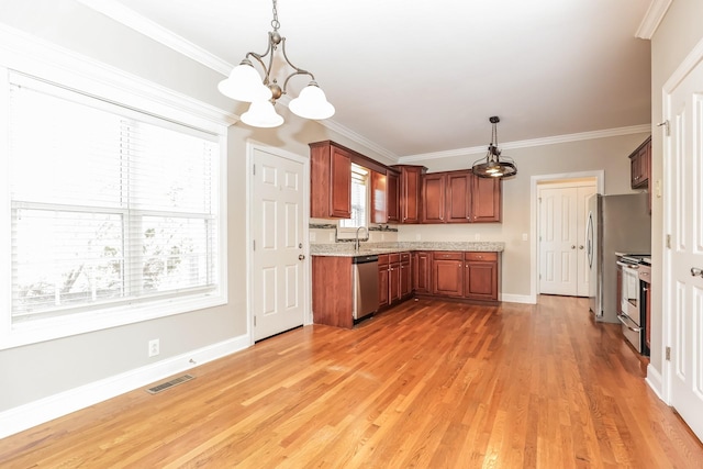 kitchen featuring visible vents, light wood-style flooring, hanging light fixtures, appliances with stainless steel finishes, and crown molding