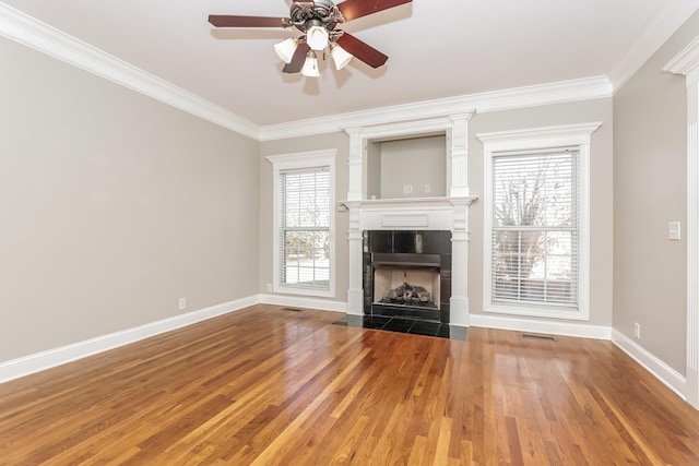 unfurnished living room featuring a fireplace, crown molding, baseboards, and wood finished floors