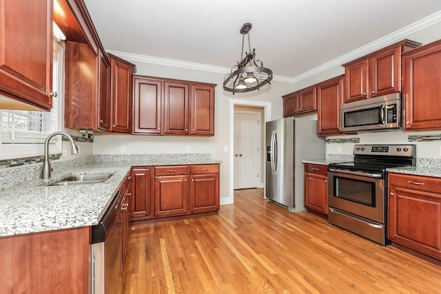 kitchen featuring light stone counters, a sink, ornamental molding, stainless steel appliances, and light wood-type flooring