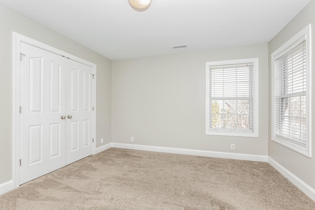 unfurnished bedroom with a closet, baseboards, visible vents, and carpet floors