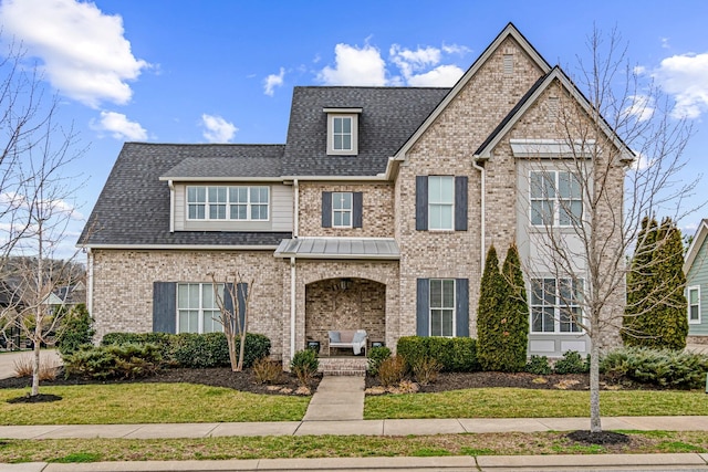 view of front of home featuring brick siding, a porch, a front lawn, and a shingled roof