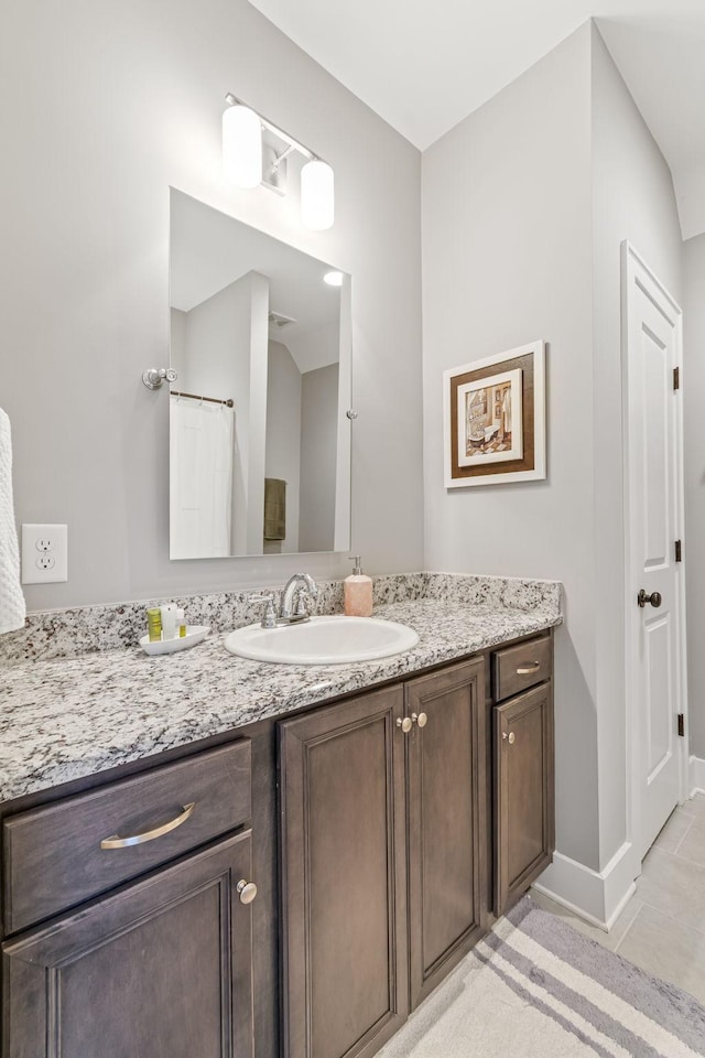 bathroom with baseboards, vanity, and tile patterned flooring