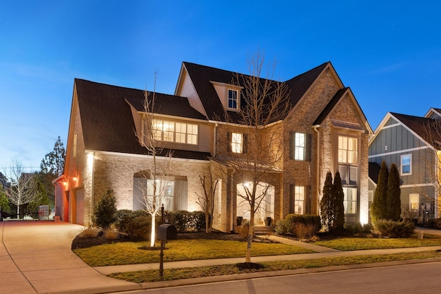 view of front of home featuring a front yard, an attached garage, brick siding, and driveway