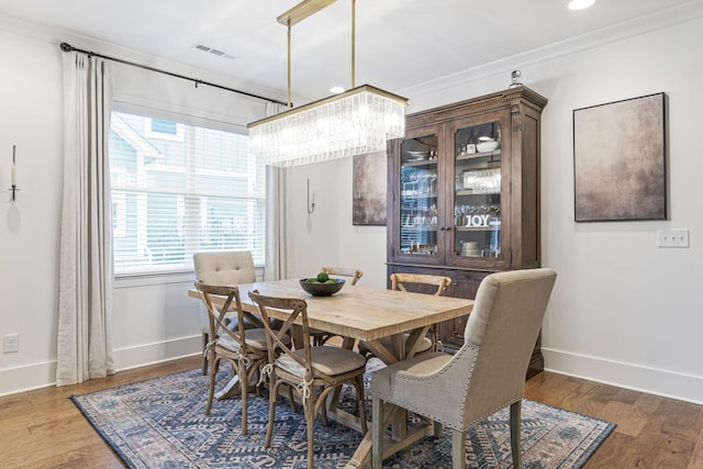 dining room featuring visible vents, crown molding, baseboards, and wood finished floors