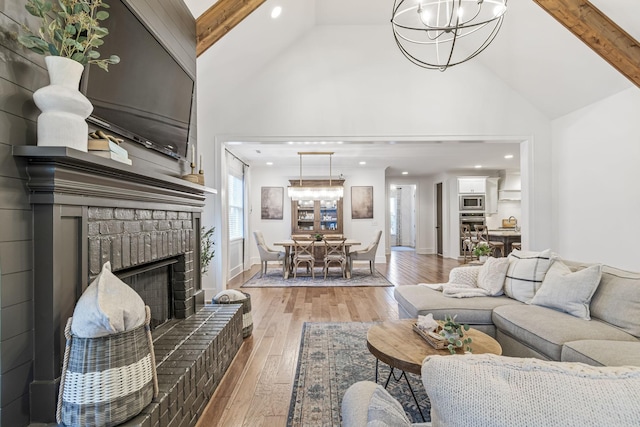 living room featuring wood-type flooring, high vaulted ceiling, beam ceiling, and a chandelier