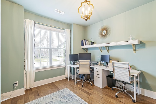 office space featuring visible vents, baseboards, a notable chandelier, and wood finished floors